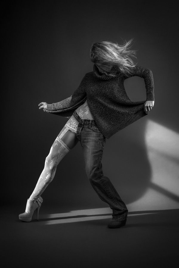 Black and white portrait of a blonde woman wearing both white lace lingerie and a wool sweater with a one-legged jean her hair floating in the wind by Artmood Visualz